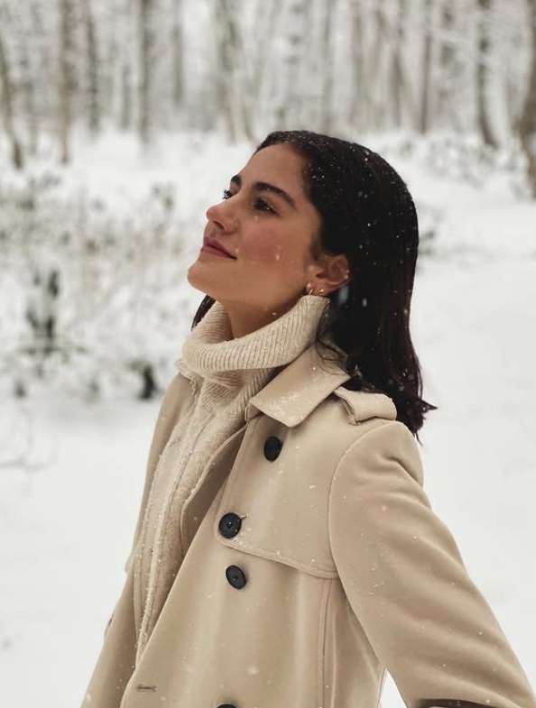 Cream trench coat over a turtleneck in falling snow