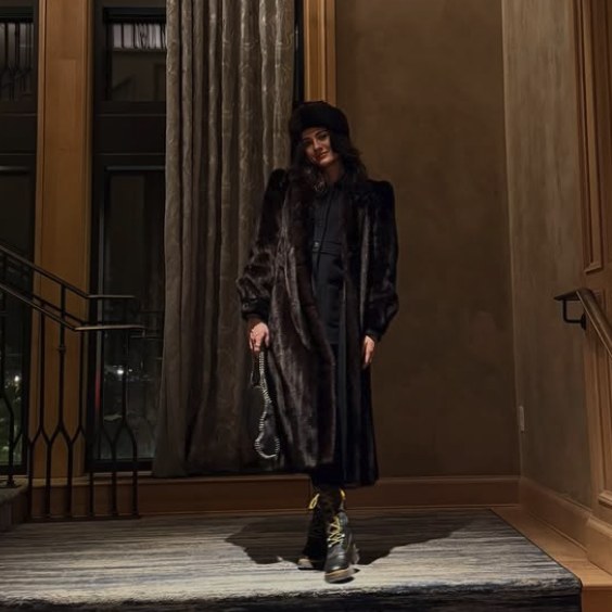 Long fur coat, beret, and lace-up boots in a hotel hall